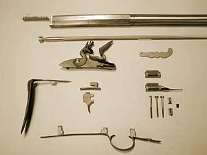 Figure 2 — The Pecatonica parts set laid out - barrel, lock, and the iron and cast furniture that you fit to the precarve stock. Nothing here drops in; every piece is inlet and shaped by hand. Source: Pecaton…
