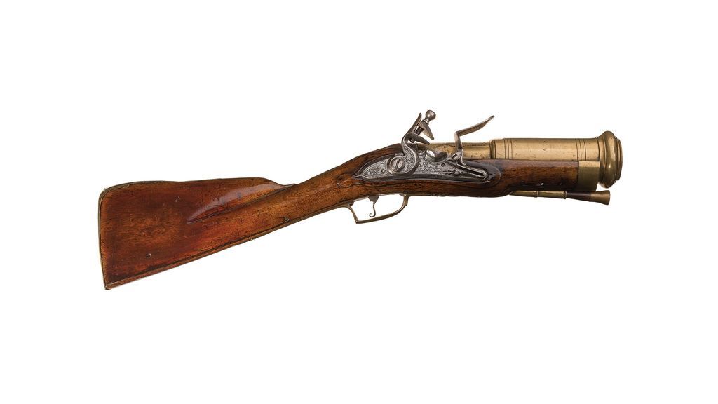 Figure 3 — A French hand mortar of the eighteenth century: a light walnut stock, an engraved lock, a short stepped brass barrel with a heavy muzzle ring, and a ramrod carried beneath. Source: via peashooter85.