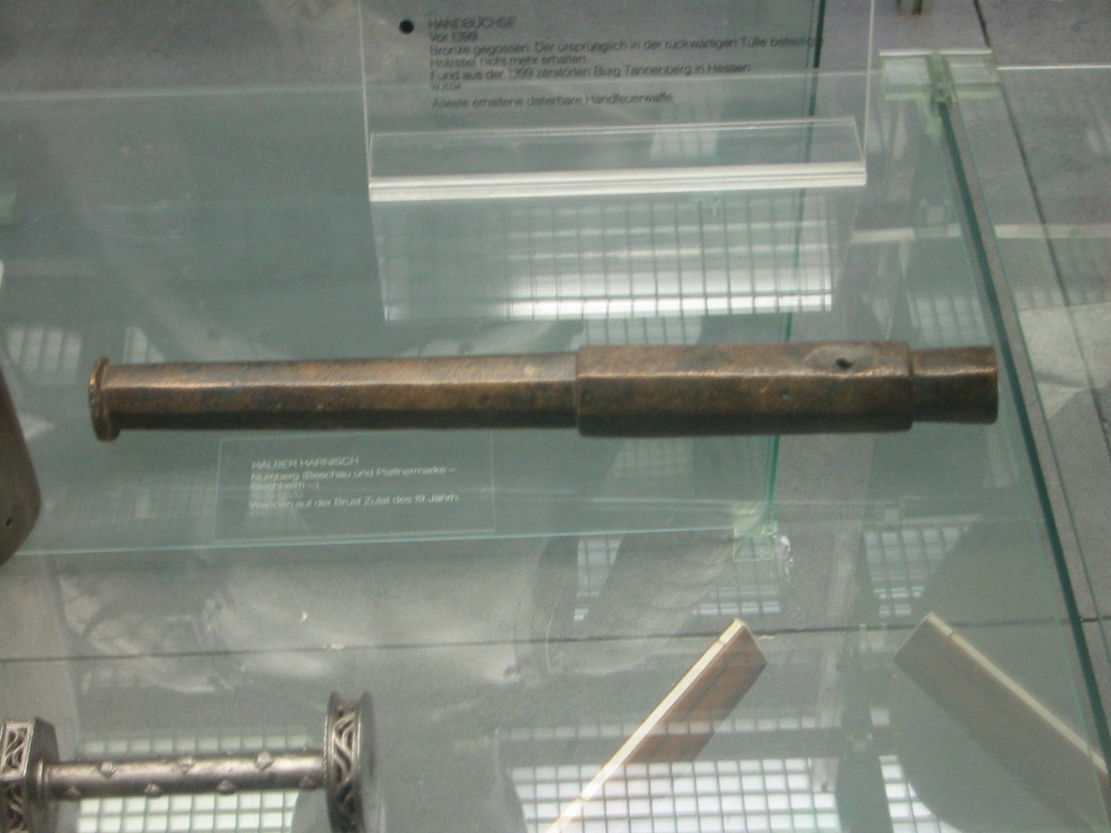 Figure 2 — The Tannenberg handgonne, the oldest firearm on Earth that can be dated with certainty — a small bronze hand cannon that must predate 1399, shown in a museum case. Source: Wikimedia Commons.