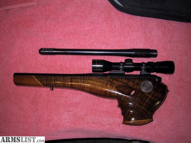 Figure 1 — An XP-100 with the barrelled action lifted out of its stock, photographed alongside the stock and a scope. The whole mechanical argument of this volume is visible here: a short rifle bolt action, a…