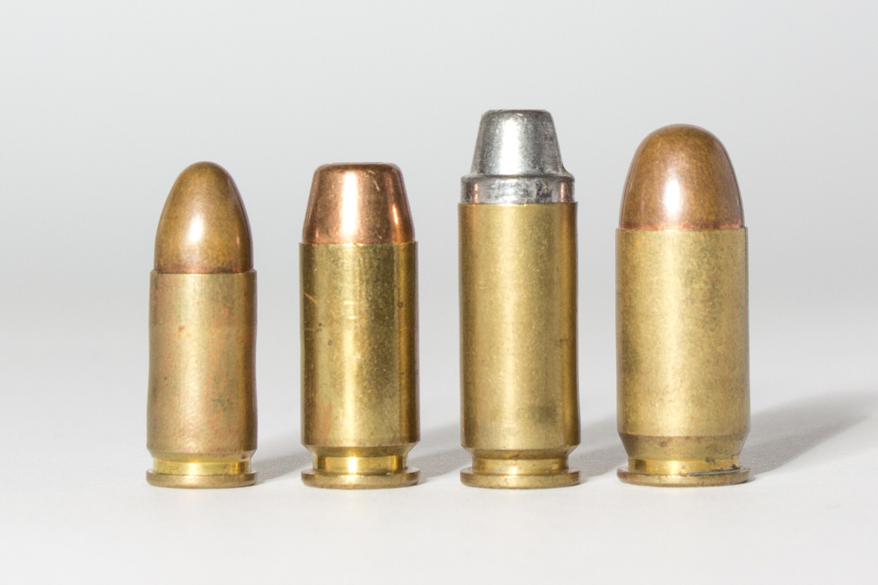 Figure 1 — Four pistol cartridges photographed together by the same author: from left, 9×19 mm, .40 S&W, 10 mm Auto and .45 ACP. The .40 is the 10 mm's diameter on a case short enough to fit a pistol built ar…