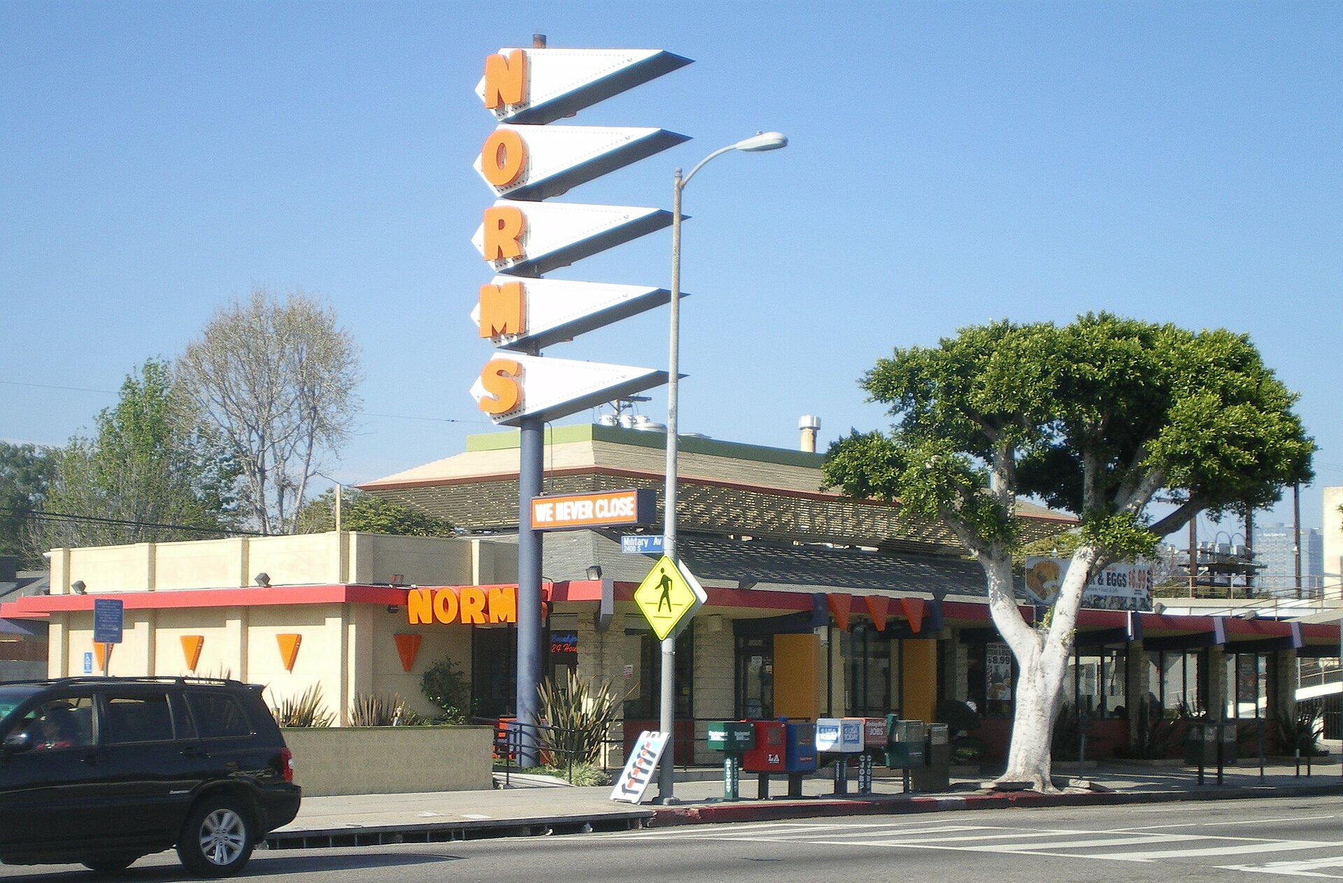Figure 5 — A Norms restaurant on Pico Boulevard, Los Angeles, with the chain's tall stepped sign of swept-back pointers — Googie roadside architecture of the kind Douglas Haskell named in 1952. Googie and the…