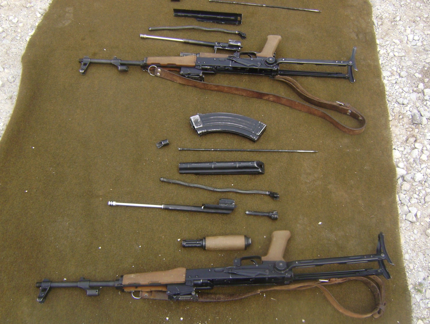 Figure 5 — An AKM field-stripped. Five groups, no tools, about forty seconds once it has been done twice: top cover, recoil spring, bolt carrier with piston, bolt, gas tube.