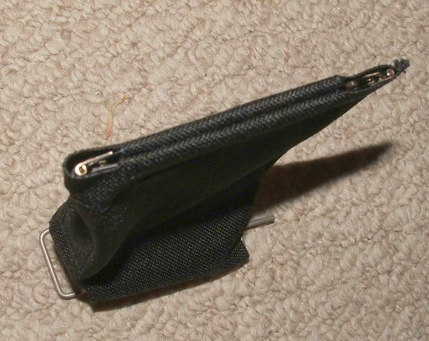 Figure 11 — The brass catcher in place over the ejection chute. Downward ejection is what makes the ambidexterity real, and the pouch is simply where the cases end up as a result.