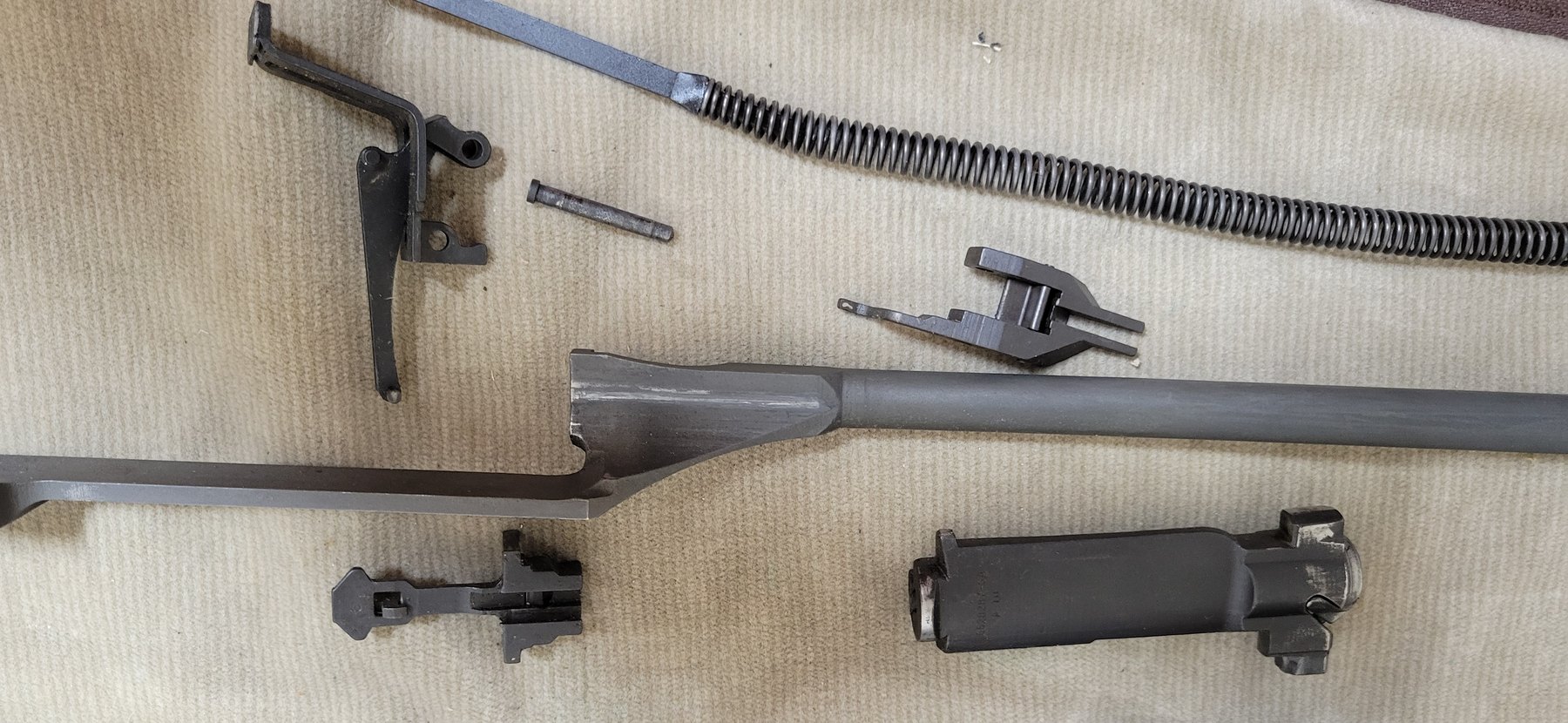 Figure 5 — Everything out: operating rod, bolt, follower rod and spring, operating rod catch and follower, laid out on the bench. These are from Springfield 2450021, the rifle documented in Vol 7.