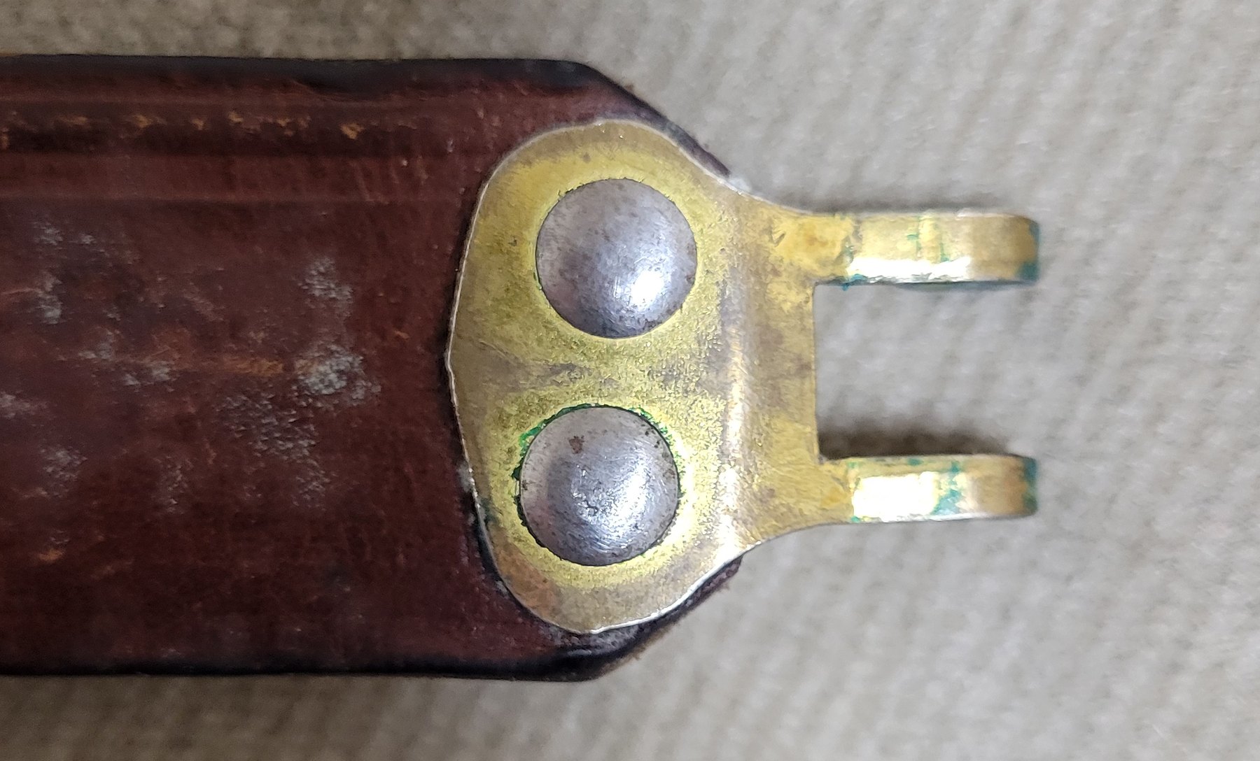 Figure 14 — The sling's claw hook from the front: two dome-headed rivets through brass.