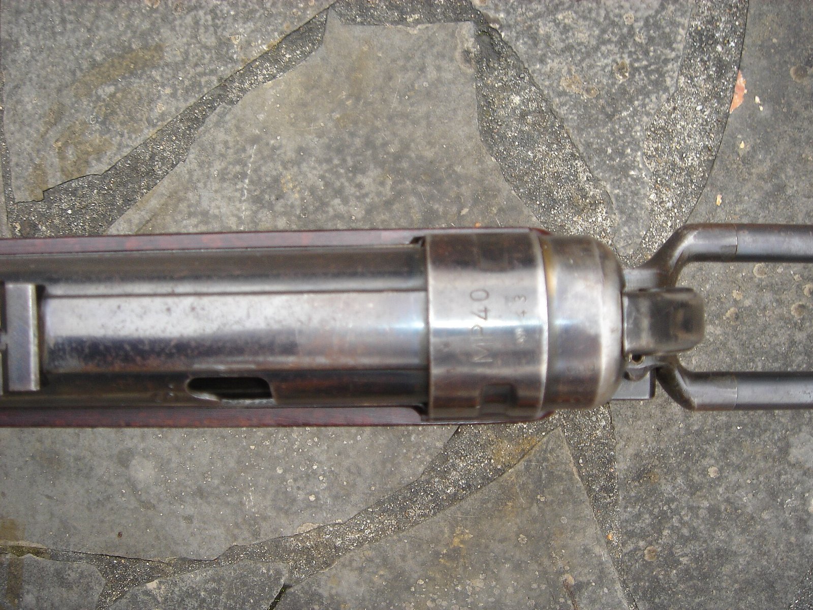 Figure 5 — The barrel collar and the forward end of the receiver. This assembly — barrel, collar, and the hooked resting bar beneath — is the conventionally machined part of an otherwise pressed and moulded w…