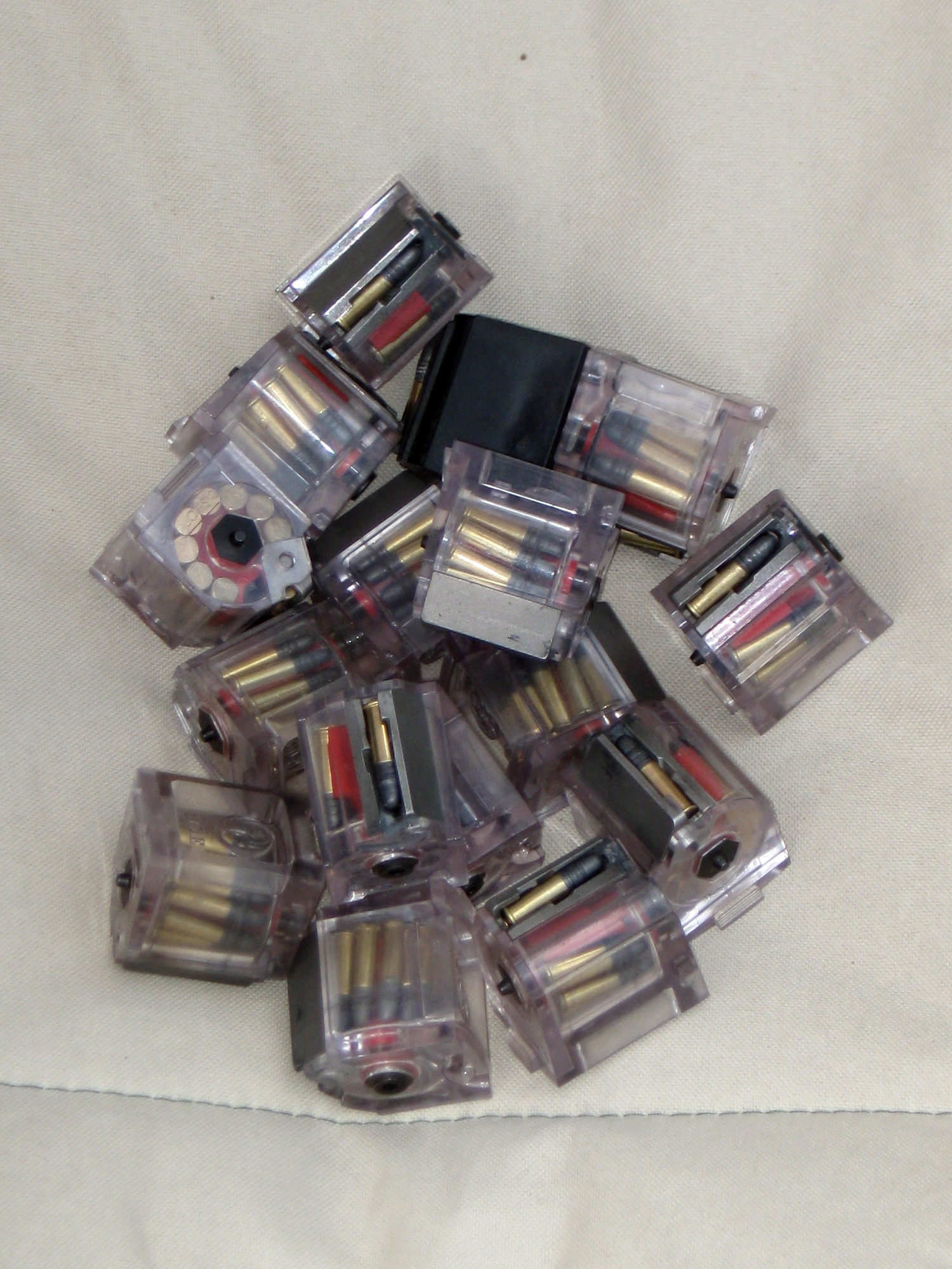 Figure 3 — Factory ten-round rotary magazines, clear-bodied, loaded. The rotor holds each round in its own pocket, so no rim ever rests on another.