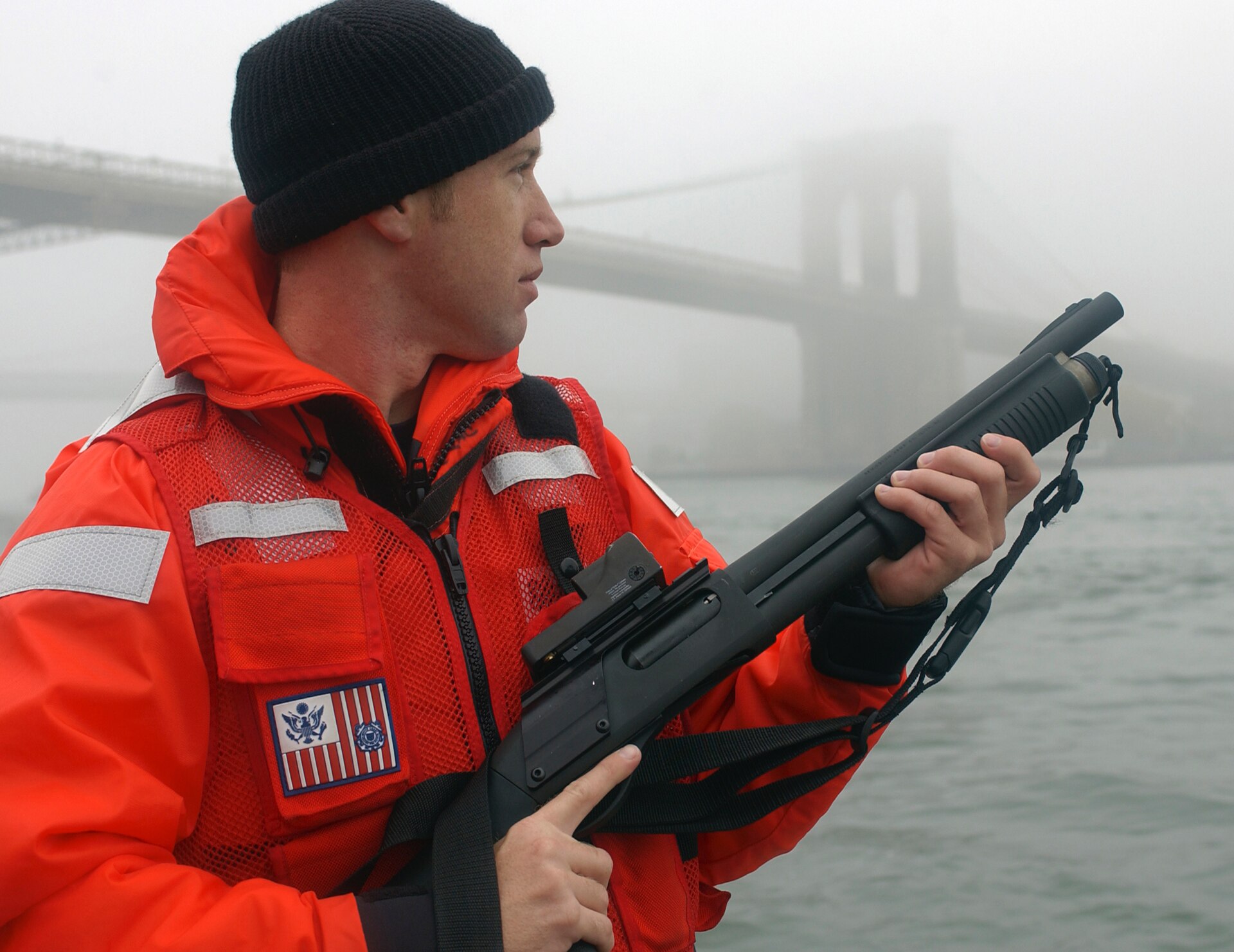 Figure 3 — A Coast Guard petty officer of a Maritime Safety and Security Team with an 870 fitted with a compact reflex sight on the receiver, New York, 2003. The reference literature identifies the gun as a M…