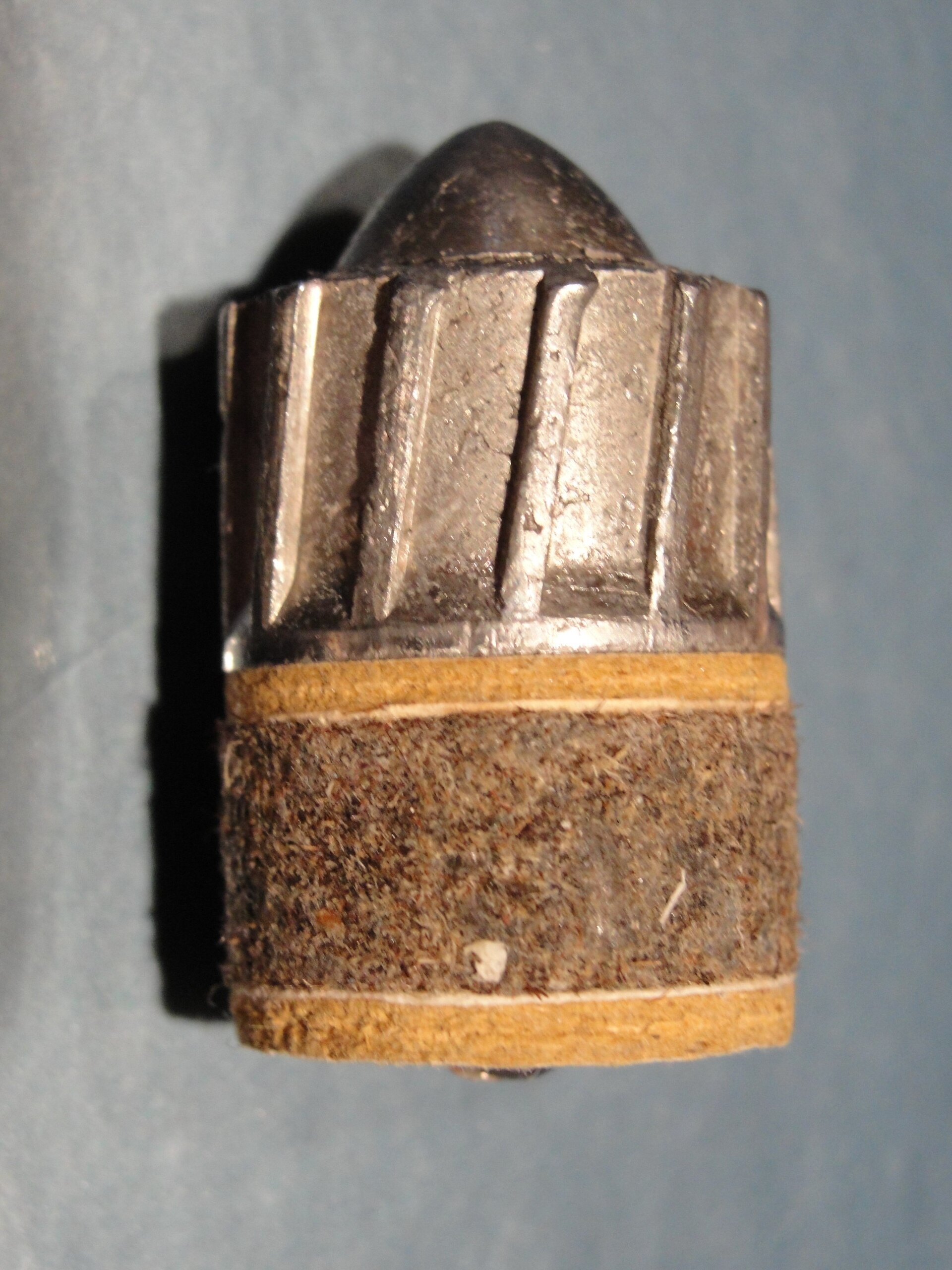 Figure 3 — A Brenneke slug photographed on end: a solid lead body with angled ribs cast on its sides and a fibre wad attached to its base. The Brenneke is the other full-bore design for smooth bores; the atta…