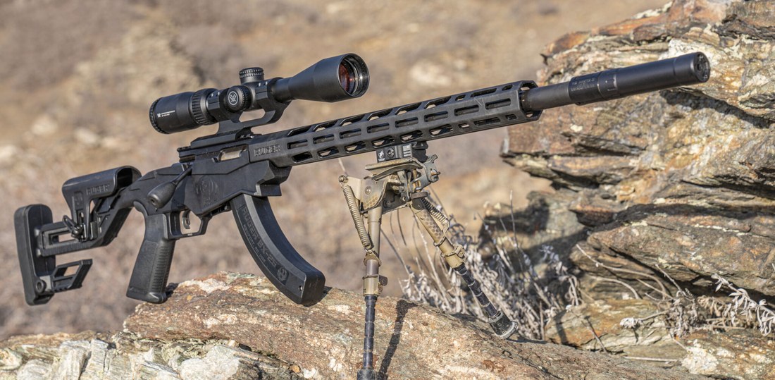Figure 3 — A Ruger Precision Rimfire, scoped and suppressed — a stock photo of the type. The free-floated heavy barrel on a chassis is the reason this is the gun in the battery that can actually resolve one a…