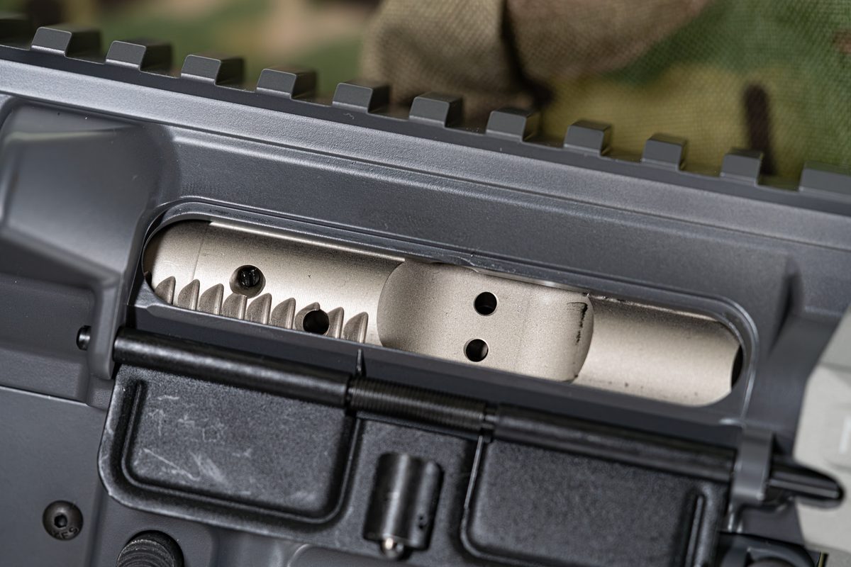 Figure 3 — An AR-15 bolt carrier group seen through the open ejection port. This is the assembled rifle; the barrel extension the bolt actually locks into is out of sight ahead of it. Photo by Tony Webster vi…