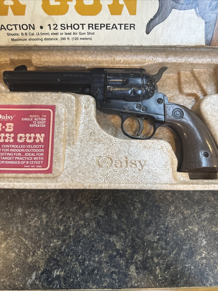 Figure 3 — A Daisy Model 179 Six-Gun with its instruction card, which prints the identification directly: "MODEL 179 / SINGLE ACTION / 12 SHOT REPEATER". The Spittin' Image styling is the argument - the ploug…