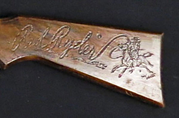 Figure 3 — The Red Ryder signature and horse-and-rider device burned into a buttstock at close range, the branded treatment of the earliest guns. No silk-screened example was available to place beside it for …