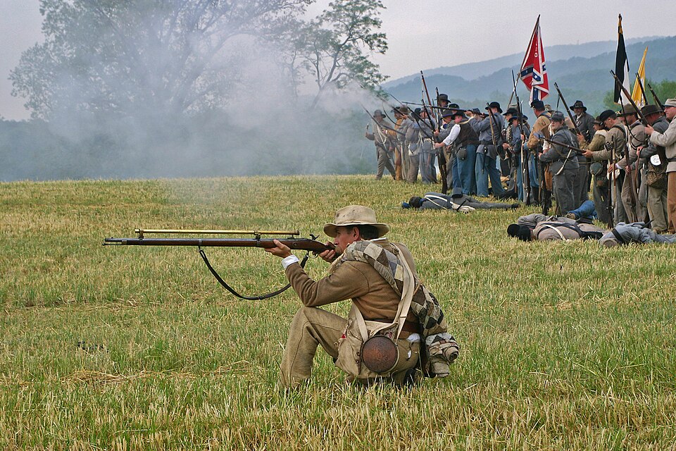 Figure 1 — Modern re-enactor with a long-tube target rifle in the Malcolm tradition. No genuine 1860s photograph of a Chapman-James or Malcolm sight is known; this is a re-enactment. Source: commons.wikimedia…